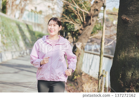 A woman in her 30s jogging outdoors. Healthy running habits. Fitness image. A woman in her 30s jogging outdoors. Healthy running habits. Fitness image. 137272162