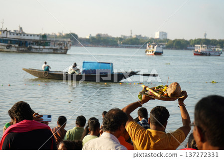 Hindu devotee holding traditional prayer offerings on a bamboo tray over his head during Chhath Puja festival at the river bank Hindu devotee holding traditional prayer offerings on a bamboo tray over his head during Chhath Puja festival at the river bank 137272331
