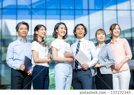 Male and female business people lined up in front of a building Male and female business people lined up in front of a building 137272345