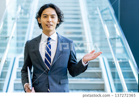 A young businessman in a suit walking down the stairs in the office 137272365