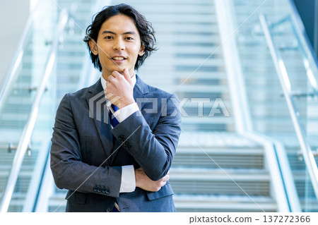 A young businessman in a suit walking down the stairs in the office A young businessman in a suit walking down the stairs in the office 137272366
