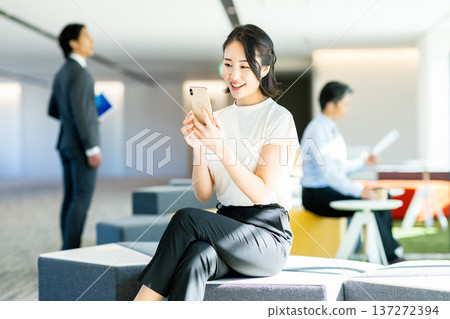 經營一部智能手機的女商人在辦公室 經營一部智能手機的女商人在辦公室 137272394