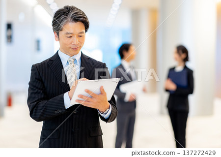商務人士在辦公室裡拿著平板電腦站著 137272429