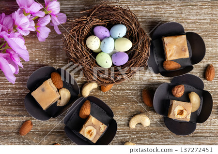 Butter fudge squares with nuts and Easter nest on wood. 137272451