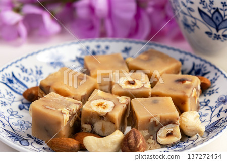 Butter fudge squares with nuts in a saucer with pink wisteria. 137272454