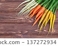 Yellow, orange and white carrots on the brown wooden table. 137272934
