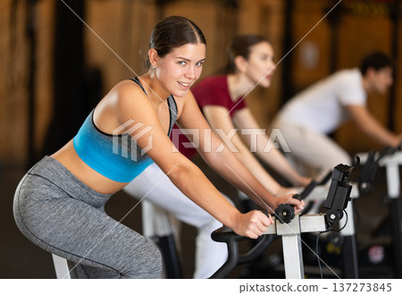 Focused girl works out with exercise bicycle during class at fitness club 137273845