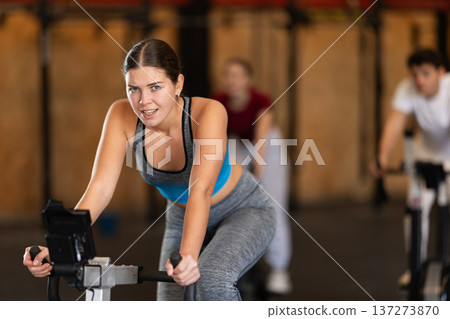 Woman in top exercising on stationary bike 137273870