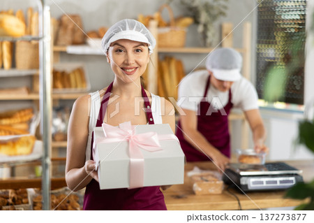 Young woman seller with box of pastries Young woman seller with box of pastries 137273877