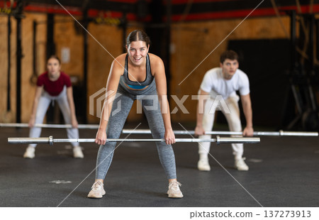Slender girl trains muscles of arms and back using barbell and differentiated weighting in gym Slender girl trains muscles of arms and back using barbell and differentiated weighting in gym 137273913