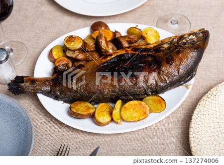 Roasted salmon carcass is accompanied by baked potato halves in their jacket Roasted salmon carcass is accompanied by baked potato halves in their jacket 137274006