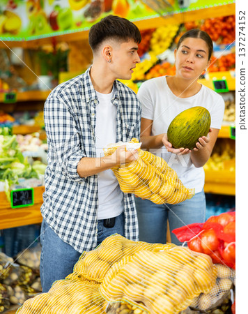 Glad young couple choosing vegetables and discussing in grocery shop. High quality photo Glad young couple choosing vegetables and discussing in grocery shop. High quality photo 137274152