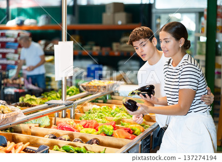 Cheerful young couple choosing ripe eggplants in farm store 137274194