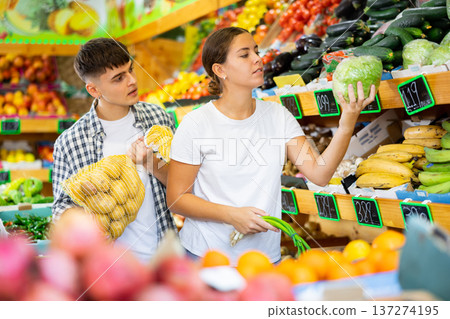 Young husband and wife choose fresh vegetables together in grocery supermarket Young husband and wife choose fresh vegetables together in grocery supermarket 137274195