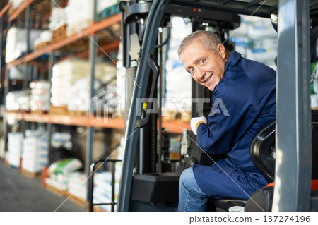 Mature man works on fork lift loader in construction rack area warehouse store repair materials. 137274196