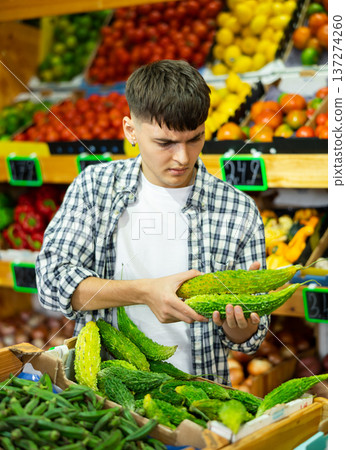 Portrait of man choosing fresh bitter melon in grocery store Portrait of man choosing fresh bitter melon in grocery store 137274260