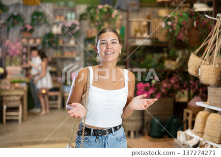 Girl buyer looks around in showroom of garden store and chooses suitable product Girl buyer looks around in showroom of garden store and chooses suitable product 137274271