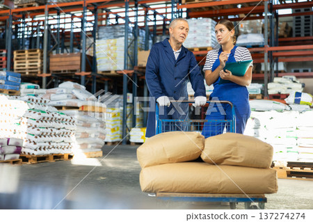 Young woman and elderly man checking documents in warehouse Young woman and elderly man checking documents in warehouse 137274274