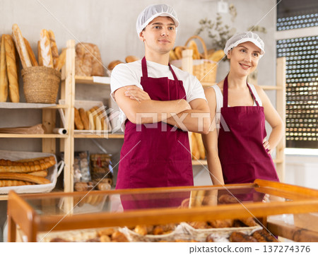 Young woman and guy sellers at counter in bakery Young woman and guy sellers at counter in bakery 137274376