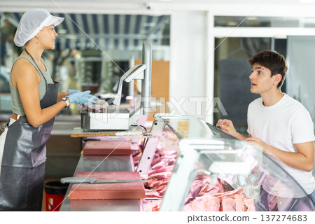 Young female seller offers guy to buy fresh beef entrecote boneless meat Young female seller offers guy to buy fresh beef entrecote boneless meat 137274683