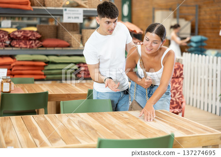 Positive young couple choosing wooden table in store 137274695