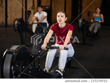Woman exercising on a rowing machine Woman exercising on a rowing machine 137274732