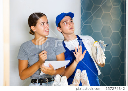 Young worker discusses project documentation of bathroom desing with a girl client 137274842