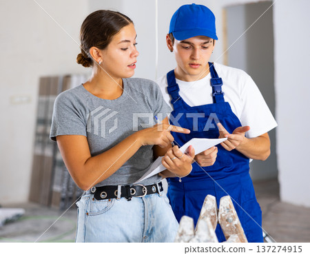 Girl homeowner discussing house renovation work plan with young builder Girl homeowner discussing house renovation work plan with young builder 137274915