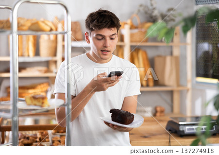 Interested guy using smartphone to analyze pastry in bakery 137274918