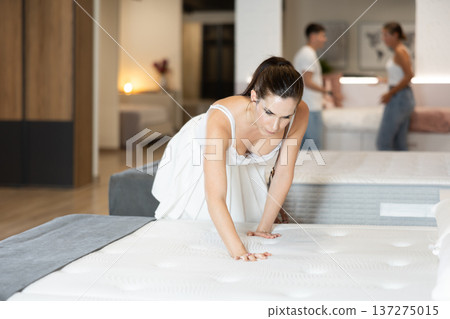 Young woman choosing convenient mattress in furniture shop Young woman choosing convenient mattress in furniture shop 137275015