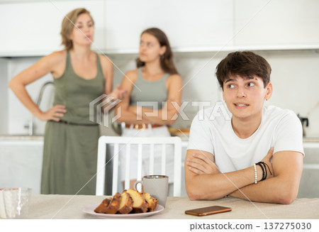 Bored guy is sitting at kitchen and unwittingly listens to mothers altercation with adult daughter Bored guy is sitting at kitchen and unwittingly listens to mothers altercation with adult daughter 137275030
