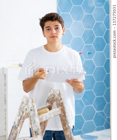 Motivated guy taking notes while working on renovation of house Motivated guy taking notes while working on renovation of house 137275031