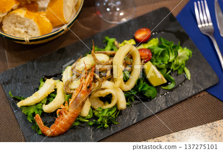 Seafood platter with fried shrimp and fish, served with lemon wedges and fresh herbs 137275101