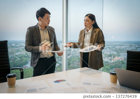 stressed two business colleagues meeting and having a serious argument or disagreement over paperwork in office 137276439