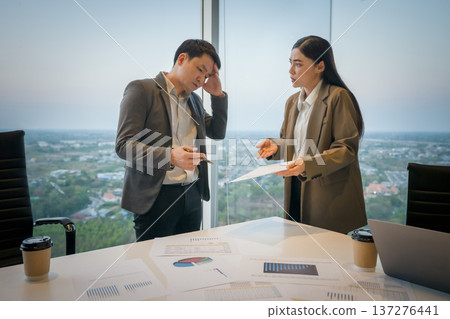 stressed two business colleagues meeting and having a serious argument or disagreement over paperwork in office 137276441