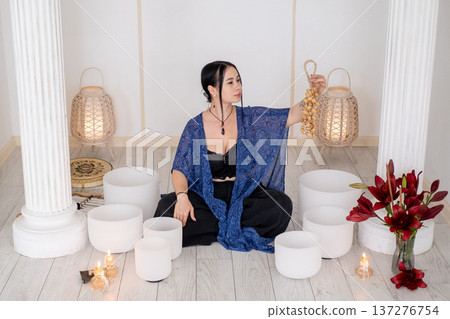 Crystal singing bowls. Meditation flow chimes. Woman enjoying sound therapy wellness retreat candles for healing treatment indoor. Crystal singing bowls. Meditation flow chimes. Woman enjoying sound therapy wellness retreat candles for healing treatment indoor. 137276754