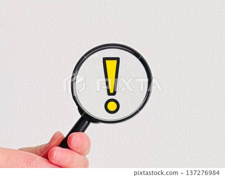 Hand holding a magnifying glass and an exclamation mark Hand holding a magnifying glass and an exclamation mark 137276984