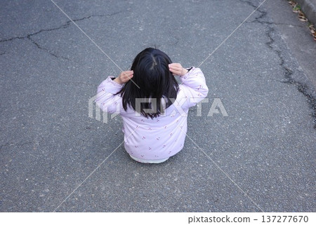 The back view of a child sitting on the road and thinking The back view of a child sitting on the road and thinking 137277670