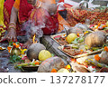 Indian Hindu devotee woman performing Chhath Puja ritual with traditional offerings on the river bank 137278177