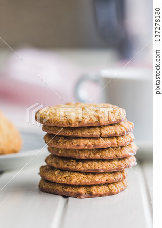Fresh oatmeal cookies on a white table with a blurred background showing a cozy setting in a kitchen 137278180