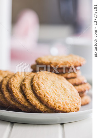Fresh oatmeal cookies on a plate with a blurred background showing a cozy setting in a kitchen 137278181