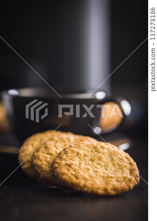 Stack of oatmeal cookies on black table with some placed beside it in a kitchen setting during daylight hours Stack of oatmeal cookies on black table with some placed beside it in a kitchen setting during daylight hours 137278186