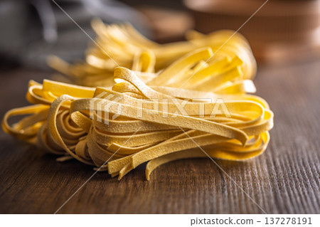 Fresh pasta ready for cooking, showing strands of fettuccine set on a wooden table. 137278191
