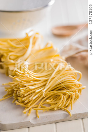 Fresh pasta ready for cooking, showing strands of bigoli set on white table. Fresh pasta ready for cooking, showing strands of bigoli set on white table. 137278196