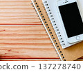 A smartphone and two notebooks placed on a wooden table 137278740