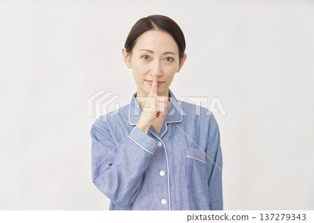 Woman in pajamas making a secret gesture on white background 137279343