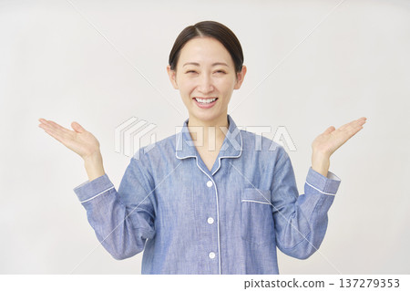 A woman in pajamas pointing left and right with her palms on a white background 137279353
