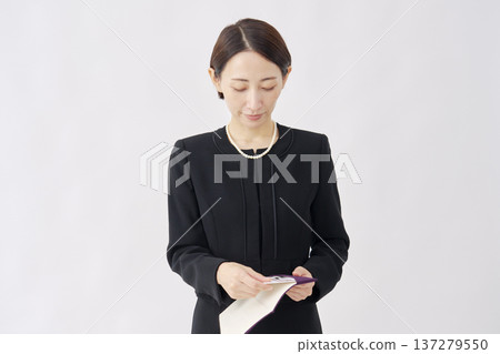 一位身著喪服的女子從一塊布中取出慰問禮物，白色背景 137279550
