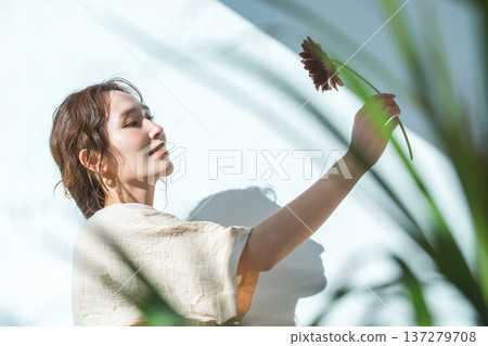 A woman holding a single gerbera flower and gazing at it 137279708