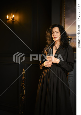 Person holds candle in dark room with art on wall and candlelight illuminating space at night Person holds candle in dark room with art on wall and candlelight illuminating space at night 137279857